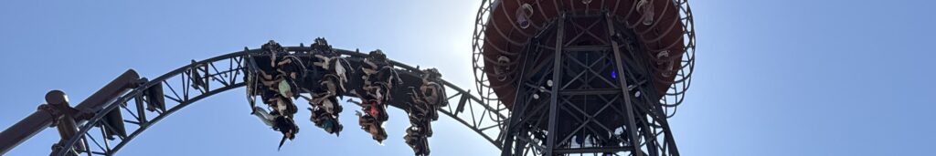 El loop de Voltron Nevera con un tren pasando y la torre de la atracción detrás